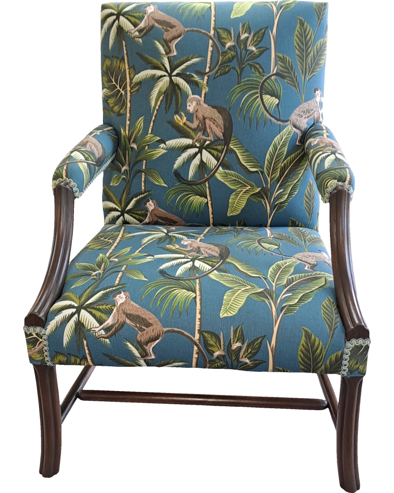 An antique chair with turquoise fabric with a monkey pattern.