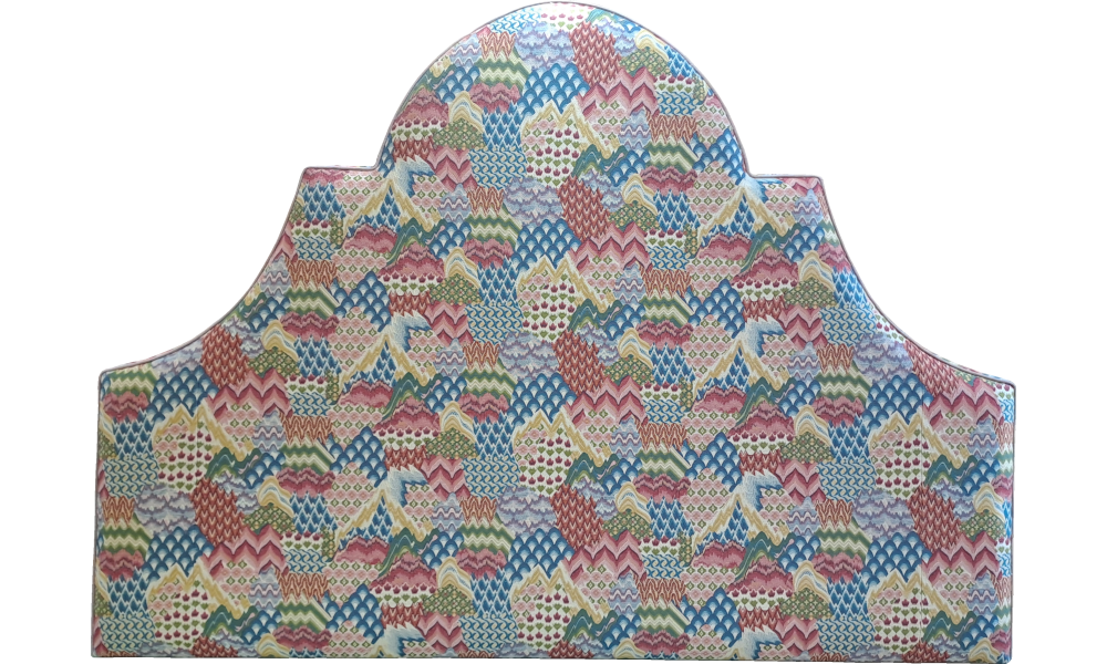 A shaped headboard with a vibrant multi-coloured pattern.